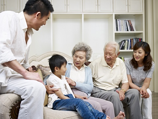 three-generation asian family talking in living room.